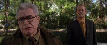 Movie still from “Rushmore” (1998), directed by Wes Anderson – An older man wearing glasses and a jacket; Close Up shot, Over the shoulder angle