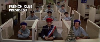 Movie still from “Rushmore” (1998), directed by Wes Anderson – A group of men sitting in a room; Wide shot, High angle