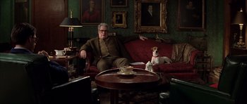 Movie still from “Rushmore” (1998), directed by Wes Anderson – A man and a dog sitting on a couch in a living room; Wide shot, Low angle