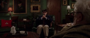 Movie still from “Rushmore” (1998), directed by Wes Anderson – A man sitting in a chair with his hands clasped together; Wide shot, Over the shoulder angle
