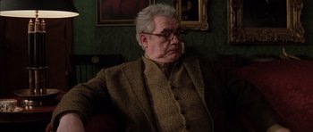 Movie still from “Rushmore” (1998), directed by Wes Anderson – An older man wearing glasses and a jacket; Medium shot, Over the shoulder angle