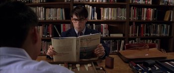 Movie still from “Rushmore” (1998), directed by Wes Anderson – A man sitting at a table reading a book; Close Up shot, High angle