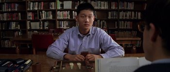 Movie still from “Rushmore” (1998), directed by Wes Anderson – A man sitting at a table in front of a book shelf; Close Up shot, Low angle