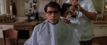 Movie still from “Rushmore” (1998), directed by Wes Anderson – A man getting his hair cut at a barber shop; Medium shot, Low angle
