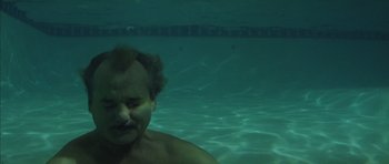 Movie still from “Rushmore” (1998), directed by Wes Anderson – A man in a swimming pool with his head above the water; Close Up shot, High angle