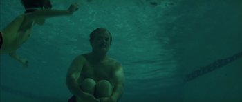 Movie still from “Rushmore” (1998), directed by Wes Anderson – A man sitting in the water with his arms crossed; Medium shot, High angle