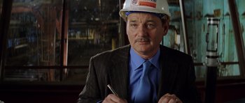 Movie still from “Rushmore” (1998), directed by Wes Anderson – A man in a suit and a hard hat holding a pencil; Close Up shot, Over the shoulder angle