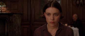 Movie still from “Rushmore” (1998), directed by Wes Anderson – A young woman with a pearl necklace looking at the camera; Close Up shot, Low angle