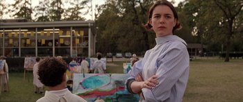 Movie still from “Rushmore” (1998), directed by Wes Anderson – A woman standing in front of a group of paintings; Medium shot, Low angle