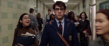 Movie still from “Rushmore” (1998), directed by Wes Anderson – A man in a suit and tie standing in front of a group of people; Medium shot, Low angle