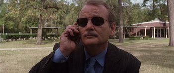 Movie still from “Rushmore” (1998), directed by Wes Anderson – An older man wearing a suit and sunglasses talking on a cell phone; Close Up shot, Low angle