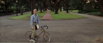Movie still from “Rushmore” (1998), directed by Wes Anderson – A young boy is standing next to a bicycle; Wide shot, Low angle