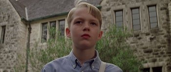 Movie still from “Rushmore” (1998), directed by Wes Anderson – A young boy with blonde hair wearing a blue shirt; Close Up shot, Low angle
