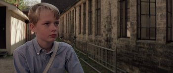 Movie still from “Rushmore” (1998), directed by Wes Anderson – A young boy standing in front of an old building; Close Up shot, Low angle