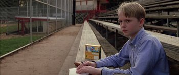 Movie still from “Rushmore” (1998), directed by Wes Anderson – A boy is sitting at a bench writing on a piece of paper; Medium shot, Low angle