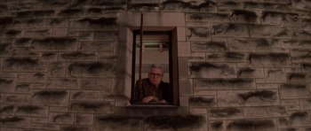 Movie still from “Rushmore” (1998), directed by Wes Anderson – A man looking out of a window at night; Wide shot, Low angle
