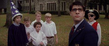 Movie still from “Rushmore” (1998), directed by Wes Anderson – A group of young men standing next to each other in a field; Medium shot, Low angle