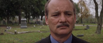 Movie still from “Rushmore” (1998), directed by Wes Anderson – An older man with a mustache is standing in a cemetery; Close Up shot, Low angle
