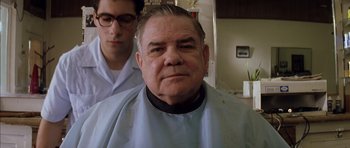 Movie still from “Rushmore” (1998), directed by Wes Anderson – An older man getting his hair cut at a barber shop; Close Up shot, Low angle