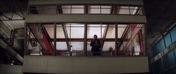 Movie still from “Rushmore” (1998), directed by Wes Anderson – A man standing in front of a large window; Wide shot, Low angle