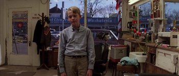Movie still from “Rushmore” (1998), directed by Wes Anderson – A young man standing in a barber shop; Medium shot, Low angle