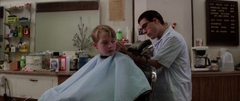 Movie still from “Rushmore” (1998), directed by Wes Anderson – A young boy getting his hair cut at a barber shop; Medium shot, Low angle