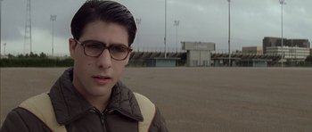 Movie still from “Rushmore” (1998), directed by Wes Anderson – A young man wearing glasses standing in an empty field; Close Up shot, Low angle