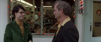 Movie still from “Rushmore” (1998), directed by Wes Anderson – A man standing in a barber shop looking at a mirror; Medium shot, Over the shoulder angle