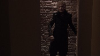 Movie still from “Russian Ark” (2002), directed by Aleksandr Sokurov – A man standing in a dark room holding a knife; Medium shot, Over the shoulder angle