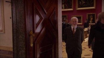 Movie still from “Russian Ark” (2002), directed by Aleksandr Sokurov – An older man standing in front of an open door; Medium shot, Over the shoulder angle