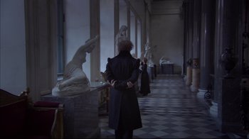 Movie still from “Russian Ark” (2002), directed by Aleksandr Sokurov – A man in a black coat is standing in a room with statues; Medium shot, Over the shoulder angle