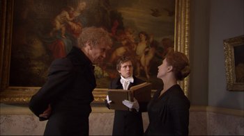 Movie still from “Russian Ark” (2002), directed by Aleksandr Sokurov – A man and a woman in a black suit holding a book; Medium shot, Over the shoulder angle
