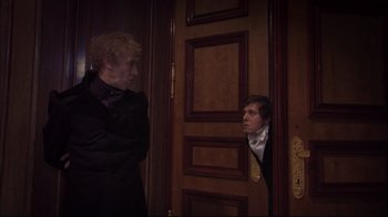 Movie still from “Russian Ark” (2002), directed by Aleksandr Sokurov – A man and a woman standing next to each other in front of a door; Medium shot, Over the shoulder angle