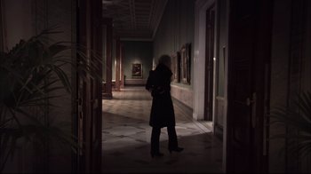 Movie still from “Russian Ark” (2002), directed by Aleksandr Sokurov – A woman is standing in a dark hallway; Wide shot, Low angle