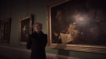 Movie still from “Russian Ark” (2002), directed by Aleksandr Sokurov – A woman standing in front of two paintings; Medium shot, Low angle