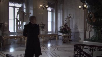 Movie still from “Russian Ark” (2002), directed by Aleksandr Sokurov – A man standing in a room with a vase of flowers on the floor; Wide shot, Over the shoulder angle