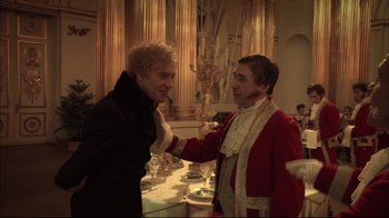 Movie still from “Russian Ark” (2002), directed by Aleksandr Sokurov – Two men in a room , one of whom is holding his hand out; Medium shot, Over the shoulder angle