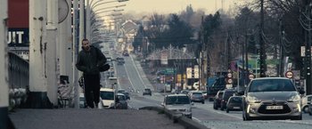 Movie still from “Rust and Bone” (2012), directed by Jacques Audiard – A person walking on the side of a road near cars; Extreme Wide shot, Low angle