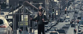 Movie still from “Rust and Bone” (2012), directed by Jacques Audiard – A man walking down the street with a child on his shoulders; Wide shot, Low angle