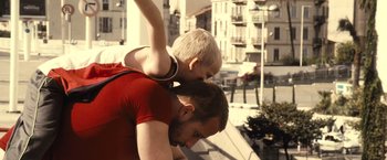 Movie still from “Rust and Bone” (2012), directed by Jacques Audiard – A man and a boy are standing on each other's shoulders; Medium shot, Low angle