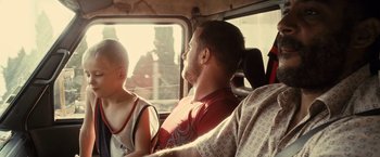 Movie still from “Rust and Bone” (2012), directed by Jacques Audiard – A man sitting next to a child in a car; Medium shot, Over the shoulder angle