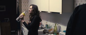 Movie still from “Rust and Bone” (2012), directed by Jacques Audiard – A woman standing in a kitchen next to a sink; Medium shot, Low angle