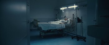 Movie still from “Rust and Bone” (2012), directed by Jacques Audiard – A man laying in a hospital bed in a room; Wide shot, High angle