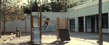 Movie still from “Rust and Bone” (2012), directed by Jacques Audiard – A man riding a skateboard down a ramp at a playground; Extreme Wide shot, High angle