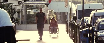 Movie still from “Rust and Bone” (2012), directed by Jacques Audiard – A man and a woman walking down a sidewalk; Wide shot, Over the shoulder angle