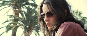 Movie still from “Rust and Bone” (2012), directed by Jacques Audiard – A person wearing sunglasses near a palm tree; Close Up shot, Low angle