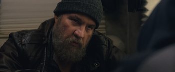 Movie still from “Rust and Bone” (2012), directed by Jacques Audiard – A man with a beard wearing a hat and jacket; Close Up shot, Over the shoulder angle