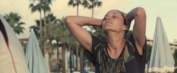 Movie still from “Rust and Bone” (2012), directed by Jacques Audiard – A woman standing in front of some palm trees; Close Up shot, High angle