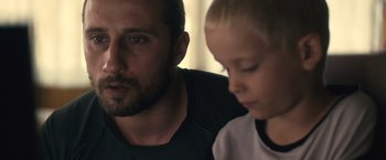 Movie still from “Rust and Bone” (2012), directed by Jacques Audiard – A man and a boy looking at a computer screen; Close Up shot, Low angle