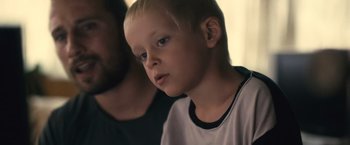 Movie still from “Rust and Bone” (2012), directed by Jacques Audiard – A young boy with blonde hair and blue eyes looking to his left; Close Up shot, Over the shoulder angle